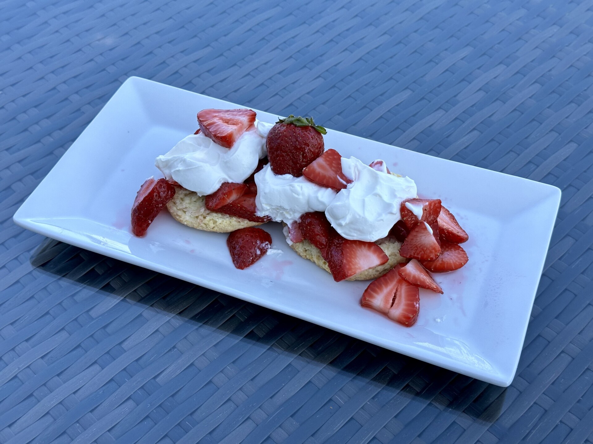 Freshly baked strawberry shortcake with juicy strawberries and whipped cream, served on a white plate.